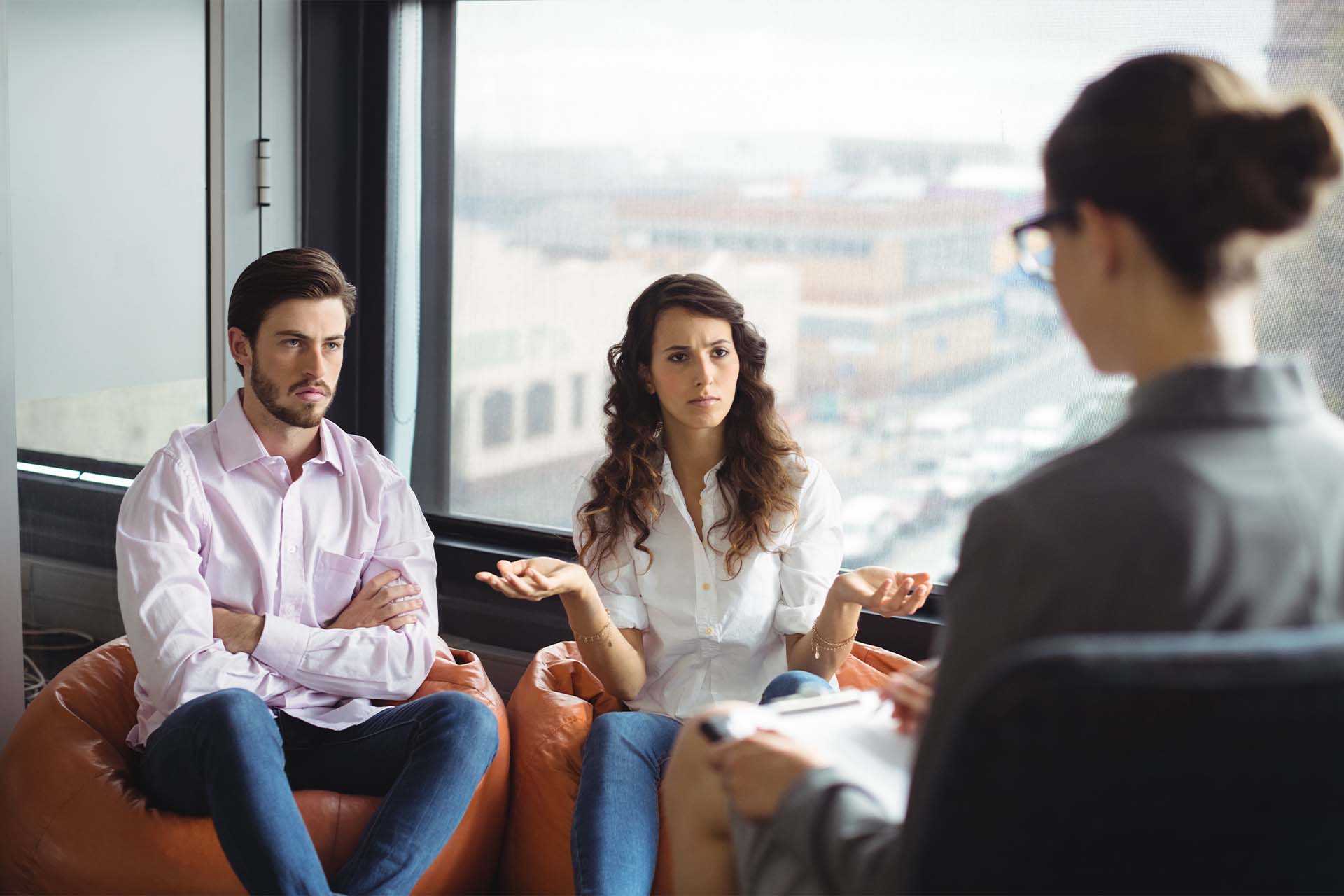 A family engaged in a Marriage and Family Therapy session, sitting together with a therapist in a circle, discussing issues in a supportive environment.